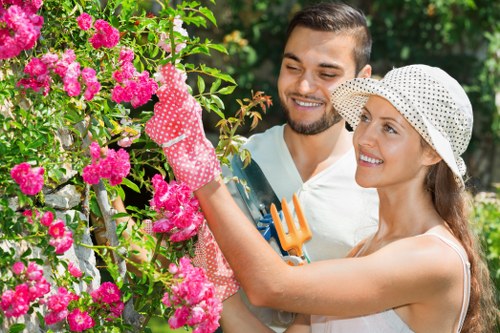Gardener preparing hedge tools beside trimmed hedgerow in Highgate