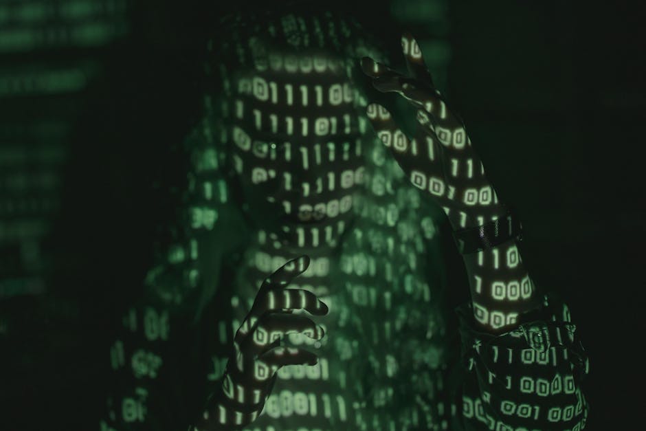 A person using a laptop on a desk, viewing a screen displaying a code editor with colorful programming lines. Their right hand holds a pen, indicating they may be making notes or modifications. The de